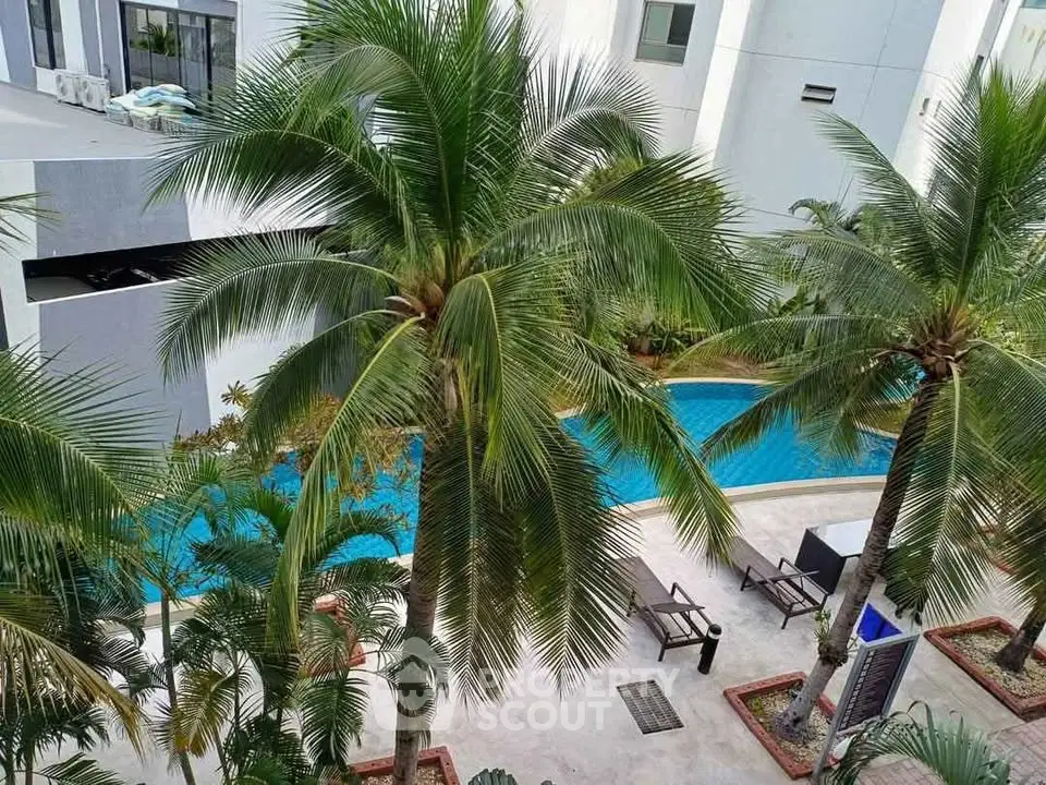 Luxurious apartment complex with tropical poolside oasis and lush palm trees.