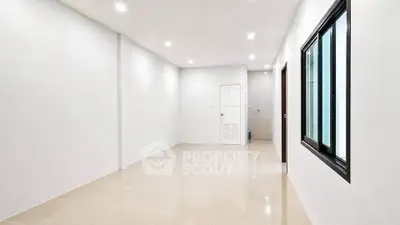 Spacious empty room with bright lighting and large window, perfect for customization.