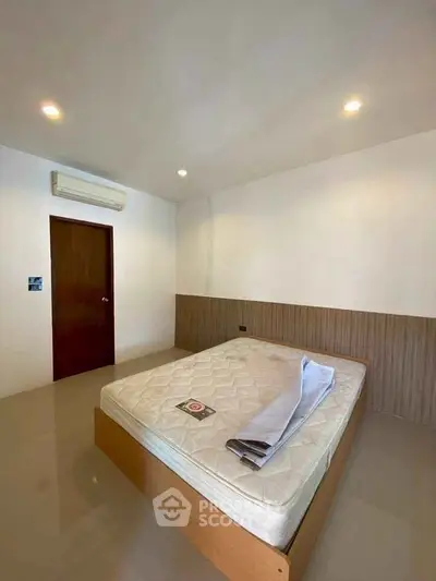 Spacious bedroom with minimalist design and air conditioning unit.