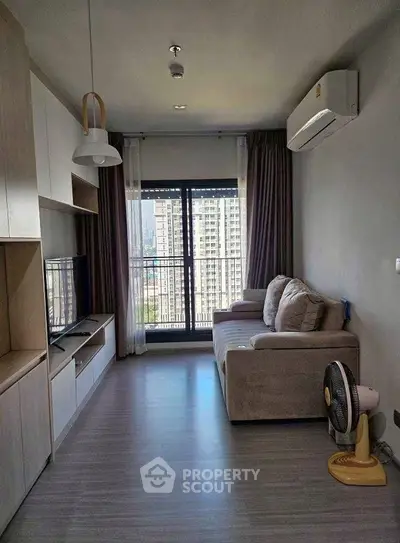 Modern living room with city view, featuring cozy sofa and sleek entertainment unit.