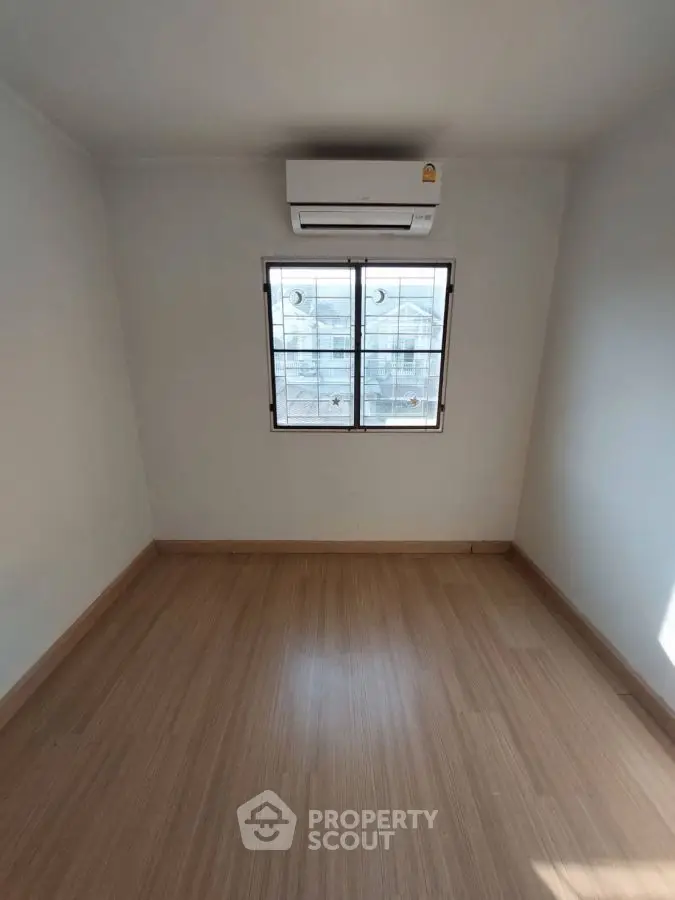 Minimalist empty room with wooden flooring and air conditioning unit