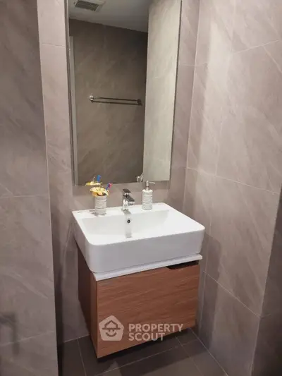 Modern bathroom with sleek sink and large mirror in stylish apartment.