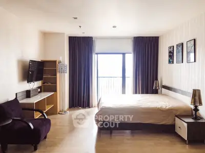 Spacious bedroom with modern decor and natural light from large window.