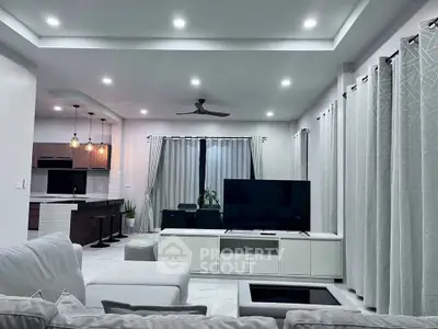 Spacious modern living room with open kitchen, stylish lighting, and elegant decor.