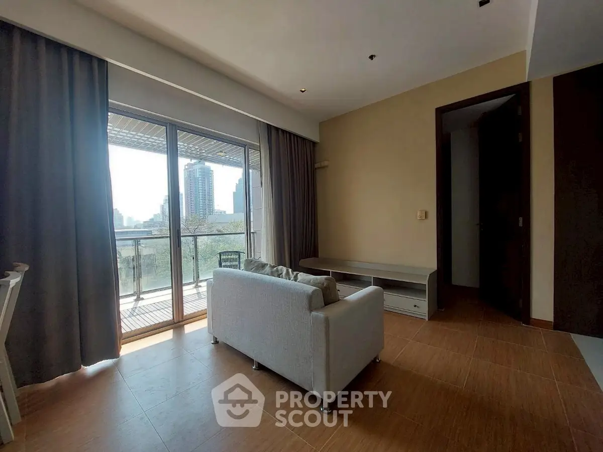 Spacious living room with large balcony and city view, perfect for relaxation and entertaining.