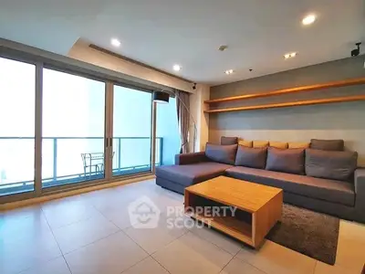 Spacious modern living room with large windows and balcony access, perfect for relaxation and entertaining.