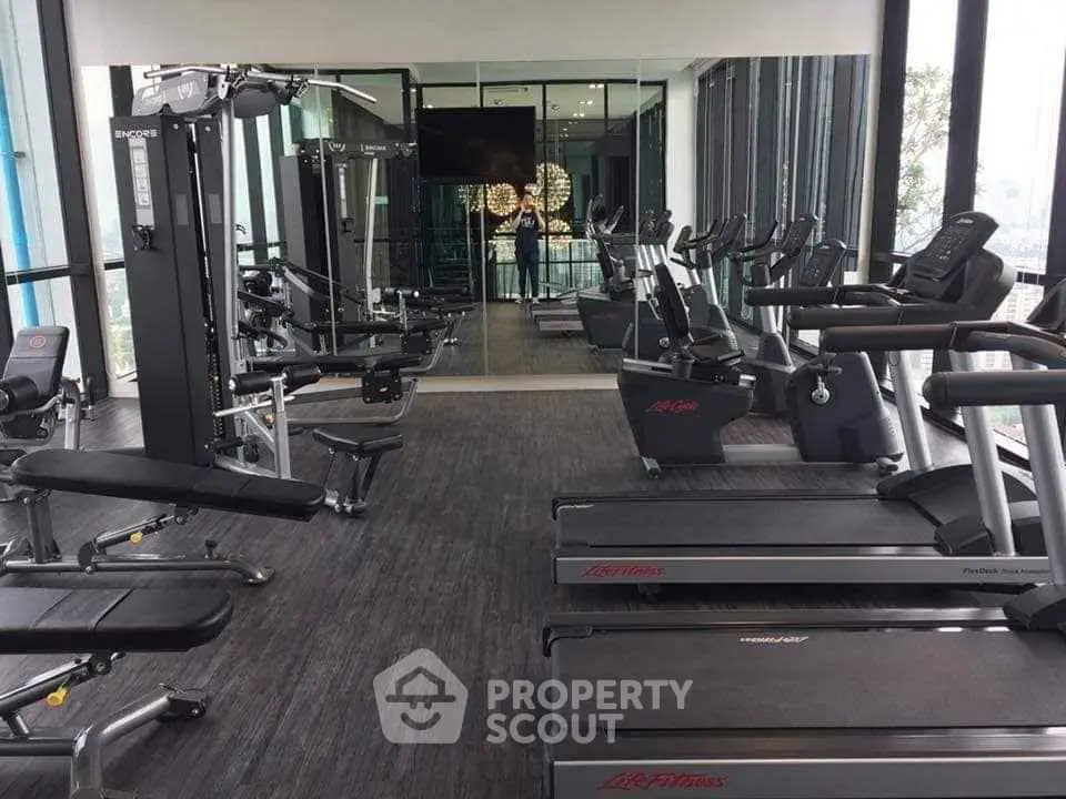 Modern gym with state-of-the-art fitness equipment and mirrored walls in a luxury building.