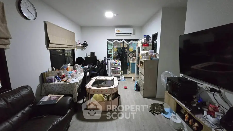 Cozy living room with modern decor, featuring a large TV, comfortable seating, and ample storage space.