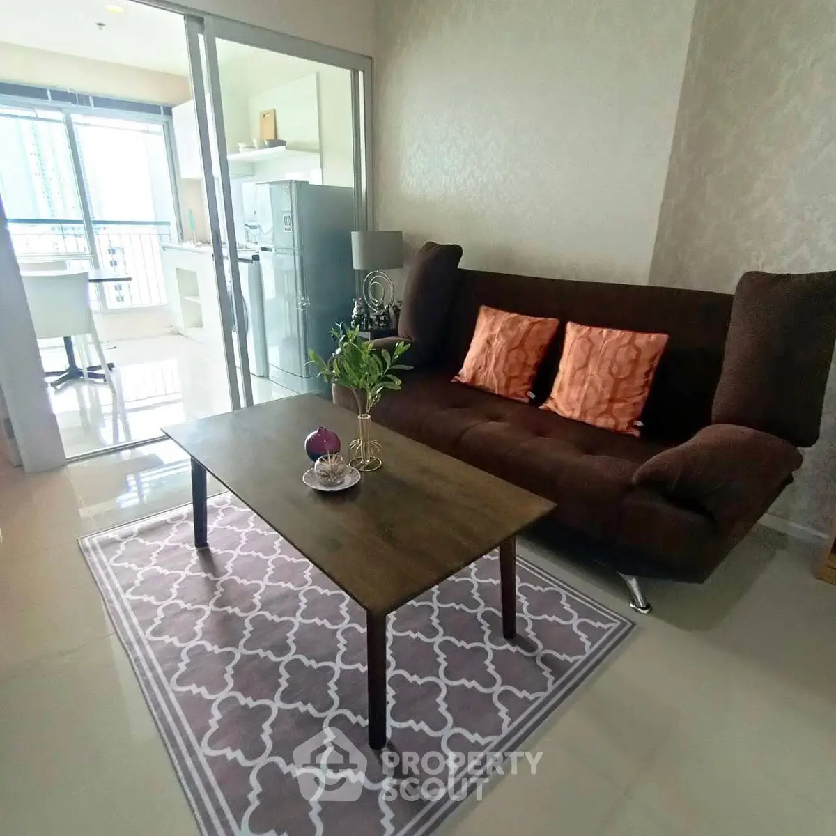 Modern living room with stylish sofa and coffee table, open layout to kitchen with balcony view.