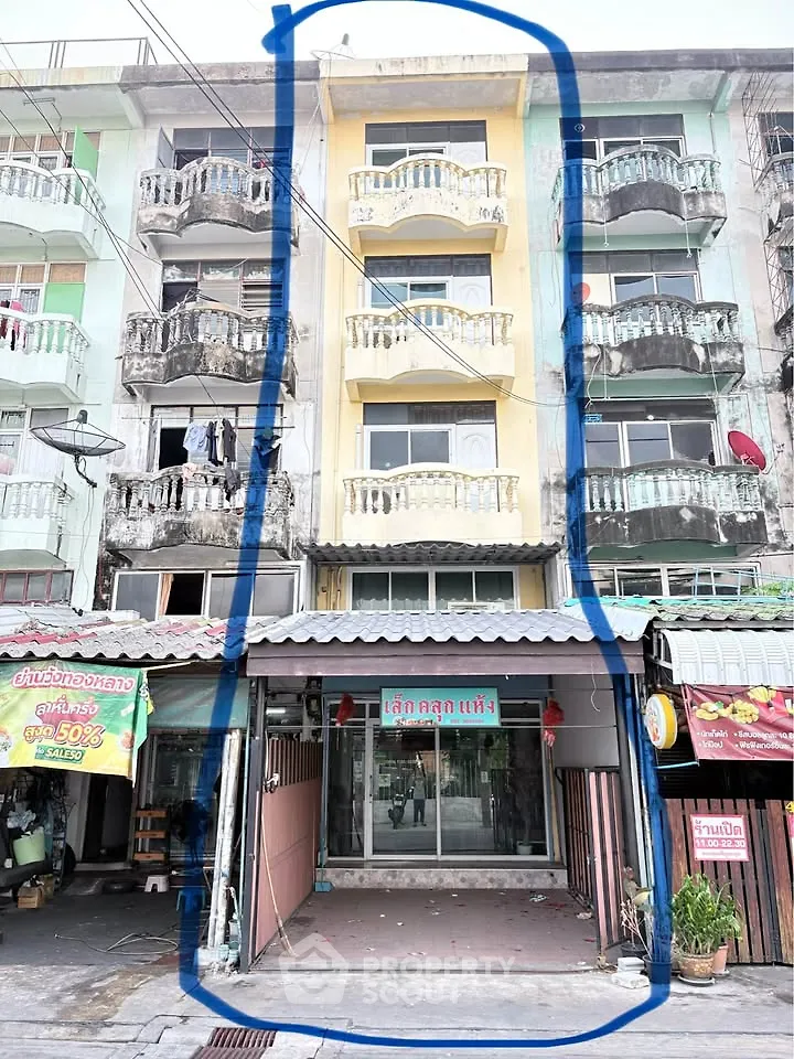 Charming multi-story building with balconies in a bustling urban area, ideal for residential or commercial use.