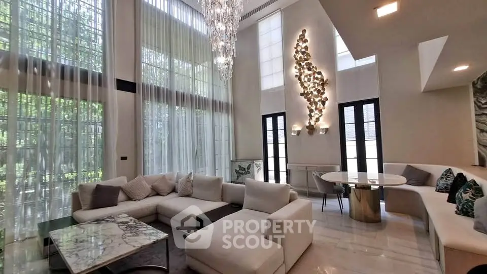 Luxurious modern living room with high ceilings, elegant chandelier, and stylish decor.