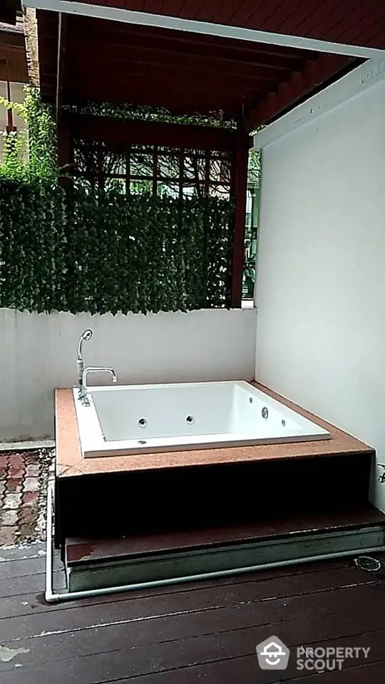 Luxurious outdoor jacuzzi with modern design, nestled in a private patio area surrounded by lush greenery, perfect for relaxation and entertainment.