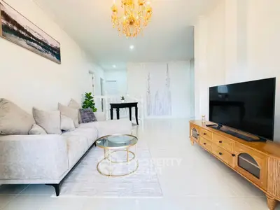 Elegant living room with plush sofa, chic chandelier, and modern TV setup