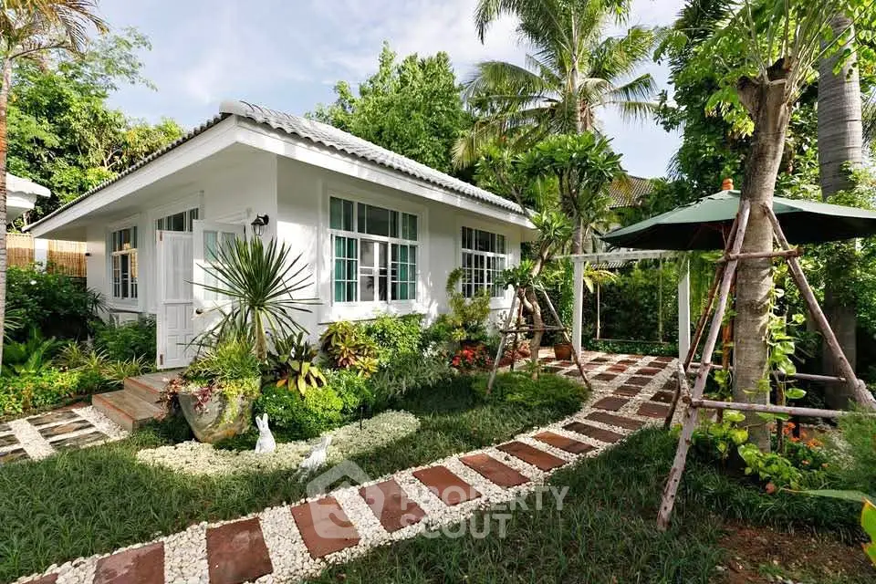 Charming white bungalow with lush garden and pathway, perfect for serene living.