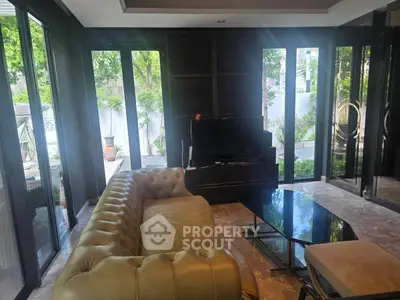 Luxurious living room with elegant leather sofa and large windows overlooking a lush garden.