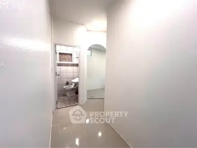 Spacious hallway leading to a modern bathroom with sleek tile flooring.