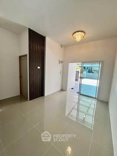 Spacious modern living room with elegant chandelier and sliding glass doors leading to a sunlit patio.
