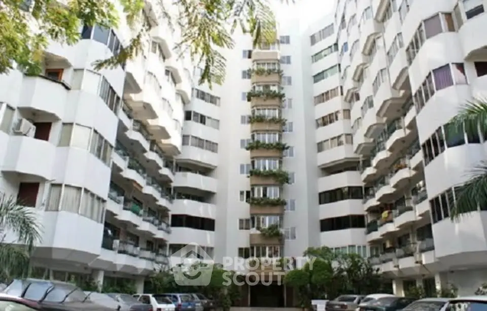 Elegant residential building with lush greenery and ample parking space.