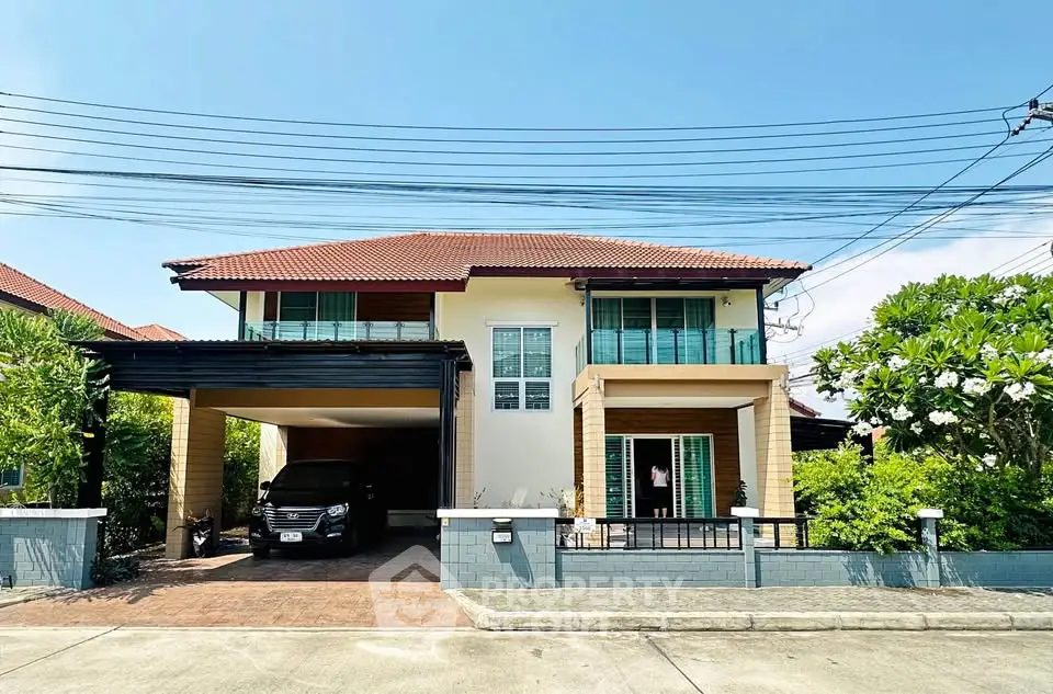 Charming two-story house with carport and lush greenery in a serene neighborhood.