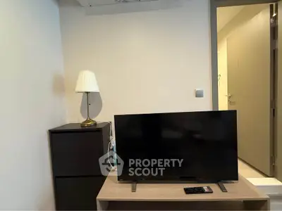 Cozy interior with modern TV setup and elegant lamp on wooden furniture.