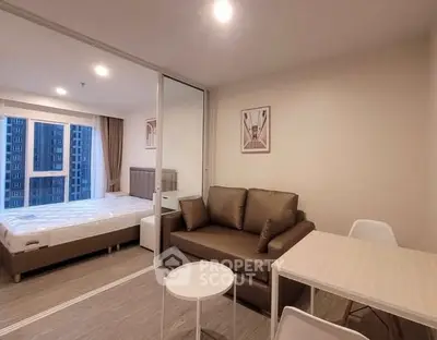 Modern studio apartment with cozy living area and bedroom, featuring sleek furniture and natural light.