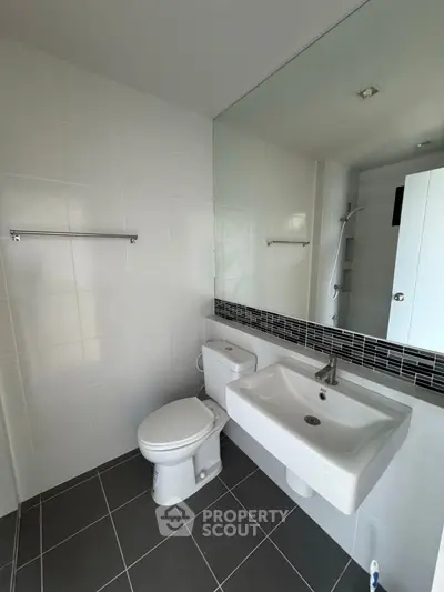 Modern bathroom with sleek fixtures and large mirror in a contemporary apartment.