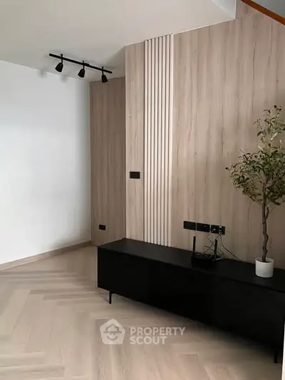 Modern minimalist living room with sleek black furniture and stylish wood paneling.