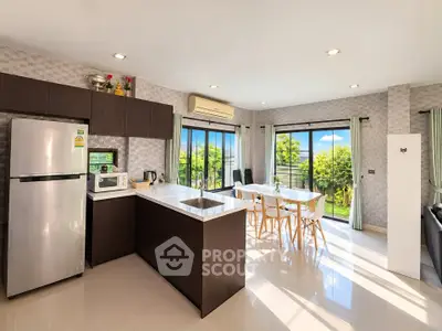 Spacious modern kitchen with open layout and dining area, featuring large windows and garden view.