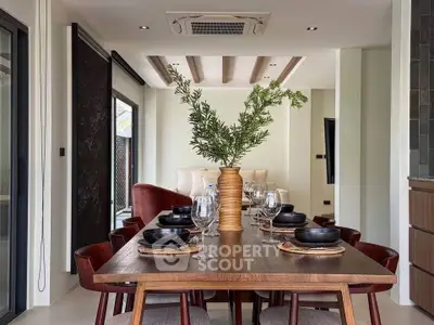 Elegant dining area with modern wooden table, stylish chairs, and decorative plant centerpiece.