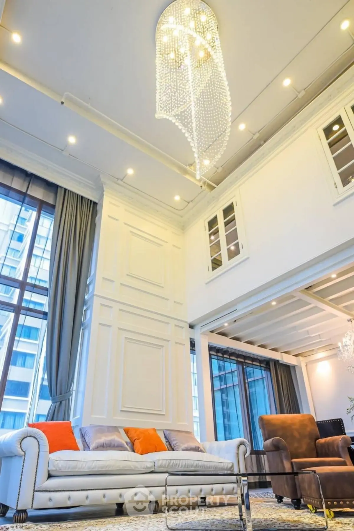 Luxurious high-ceiling living room with elegant chandelier and modern furniture