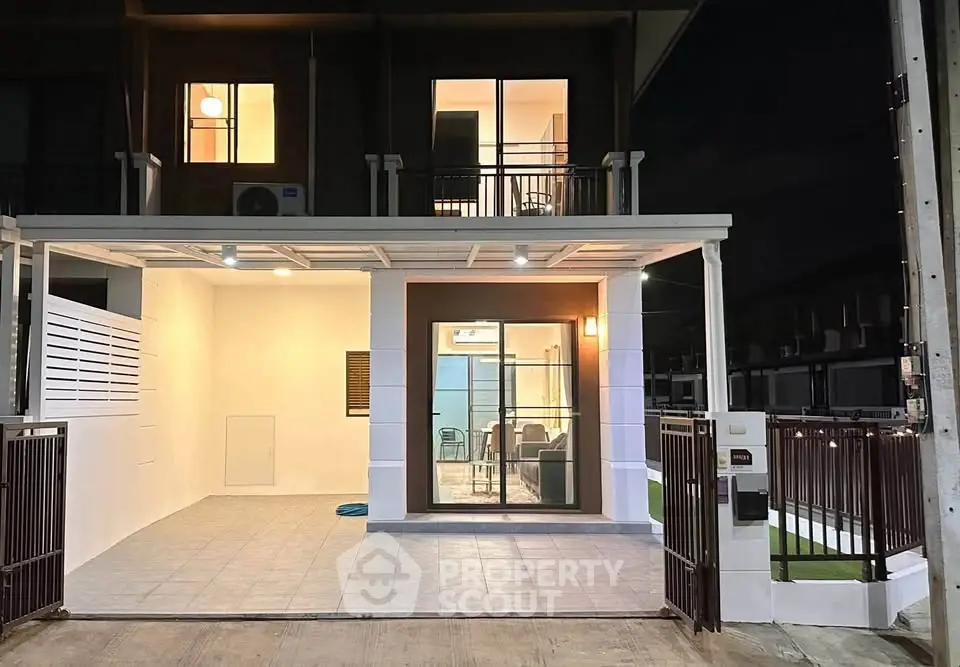 Modern townhouse exterior with spacious carport and illuminated entrance at night.