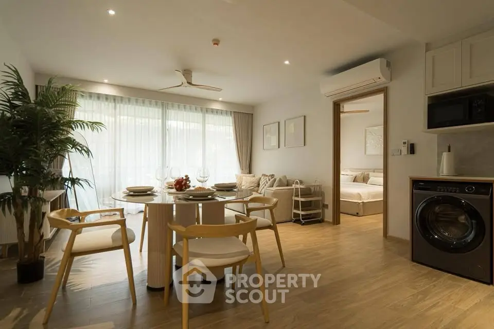 Modern open-plan living room with dining area and view into bedroom, featuring stylish decor and natural light.