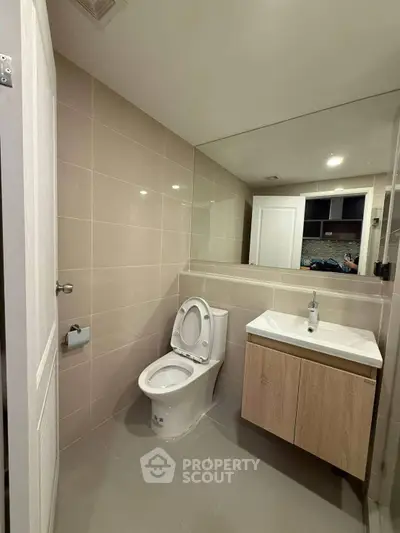 Modern bathroom with sleek fixtures and large mirror in contemporary home.
