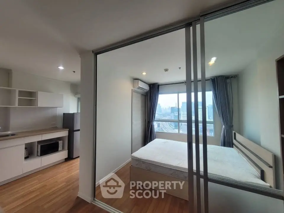 Modern studio apartment with open kitchen and city view, featuring sleek design and ample natural light.