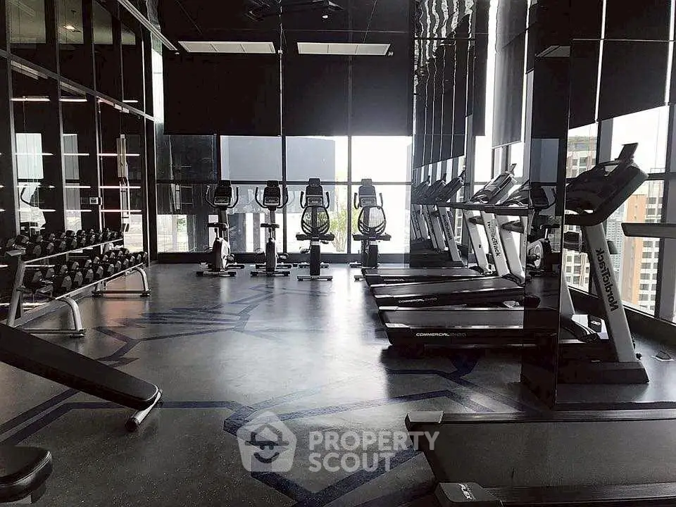 Modern gym with state-of-the-art equipment and city view in luxury apartment building.