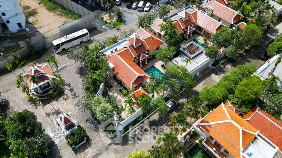 Aerial view of luxurious villa with red-tiled roofs and lush gardens.