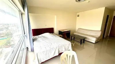Spacious bedroom with large window offering city views, modern furnishings, and ample natural light.