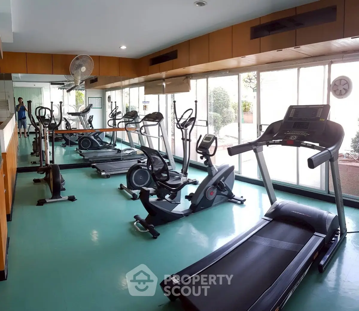 Spacious gym with modern exercise equipment and large windows for natural light.