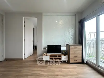 Spacious living room with wooden flooring and large windows offering city views.