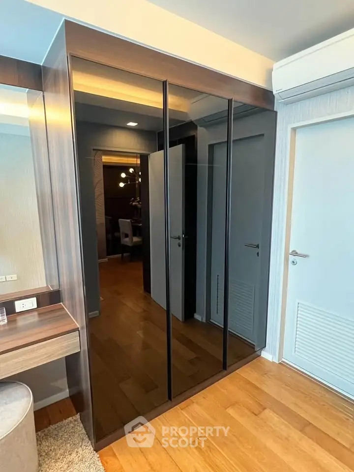 Modern bedroom with sleek mirrored wardrobe and wooden flooring