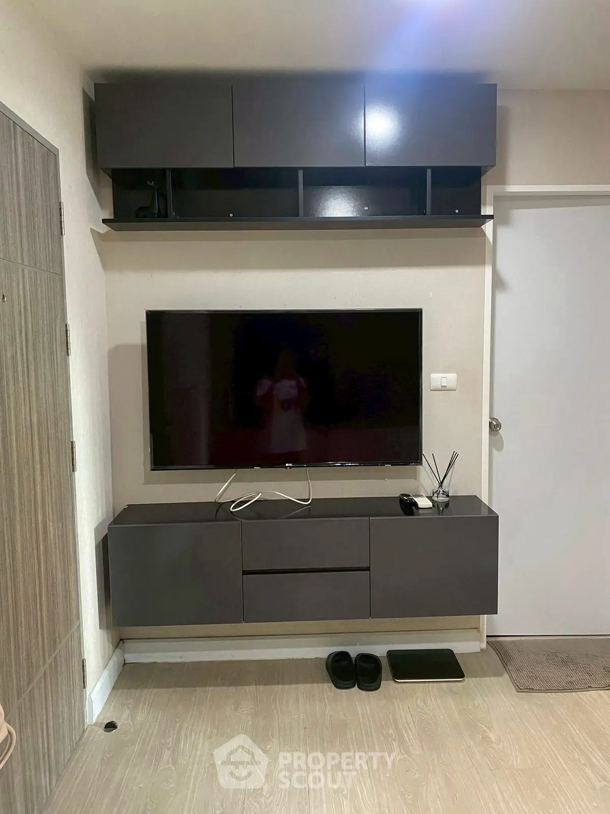 Modern living room with wall-mounted TV and sleek storage units.