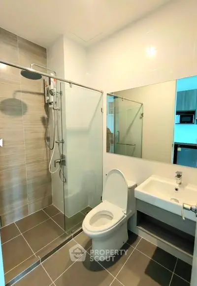 Modern bathroom with glass shower, sleek tiles, and contemporary fixtures in a stylish apartment.