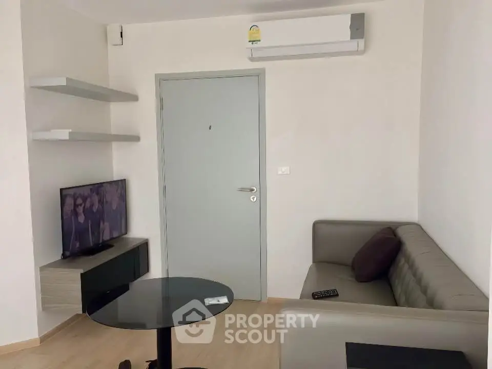 Modern living room with sleek furniture and wall-mounted TV in a cozy apartment.