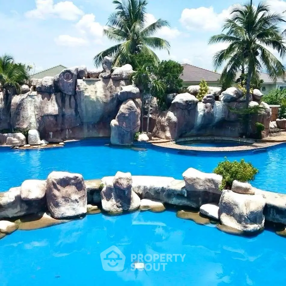 Luxurious resort-style pool with stunning rock formations and lush palm trees.