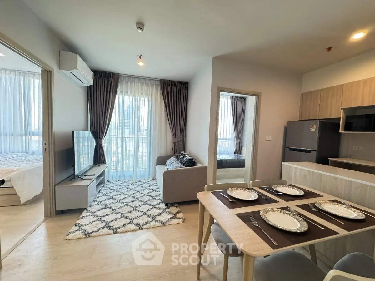 Modern open-plan living room with dining area and kitchen in stylish apartment.