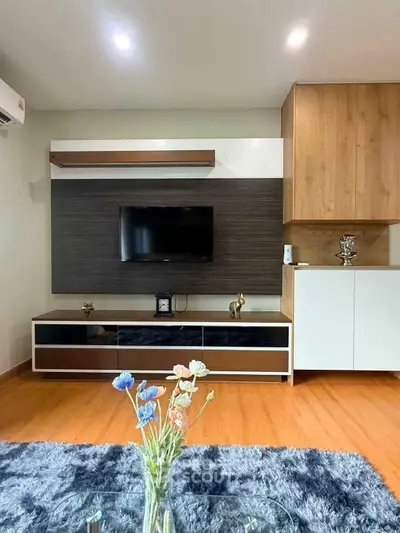 Modern living room with stylish decor and wooden flooring, featuring a sleek TV unit and elegant furnishings.