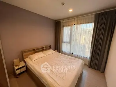 Cozy bedroom with large window and city view, featuring modern decor and natural light.