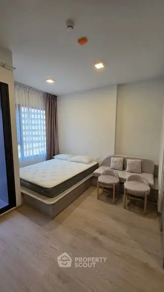 Modern bedroom with cozy bed and stylish seating area in a bright apartment.