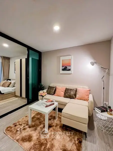 Cozy living room with modern decor and plush rug, adjacent to a stylish bedroom.