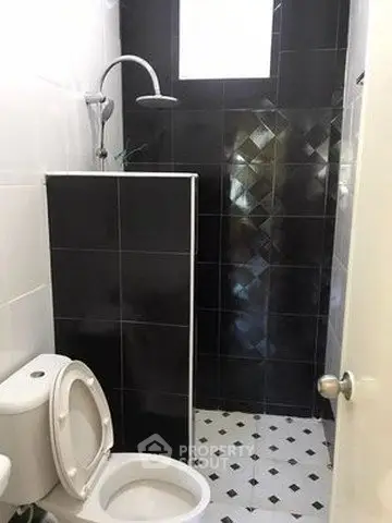 Modern bathroom with sleek black tiles and contemporary shower design.